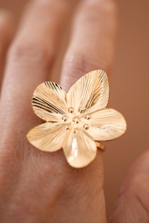 Front view of adjustable 18k gold plated flower ring on finger, showcasing the delicate design