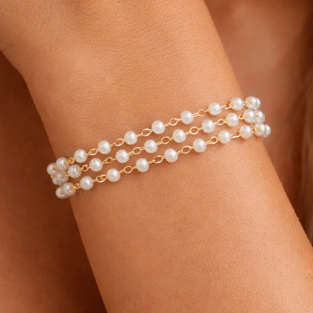 Front view of a luxurious 18k gold plated pearl bracelet on a model's wrist
