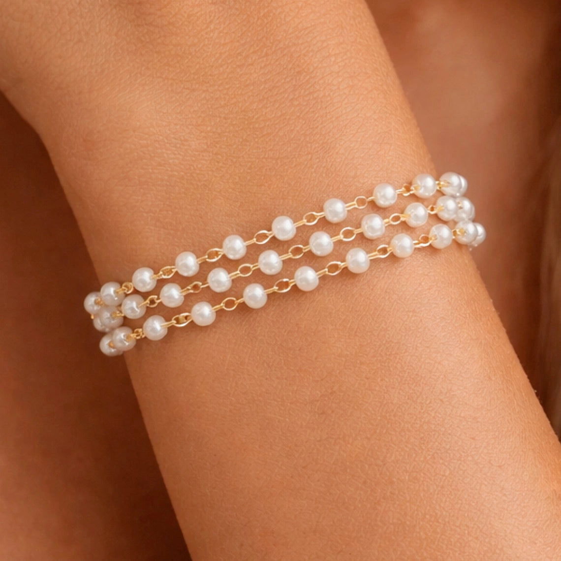Front view of a luxurious 18k gold plated pearl bracelet on a model's wrist