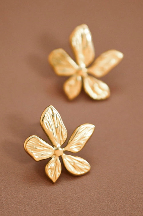18K gold plated stainless steel blooming flower stud earrings held between fingers.