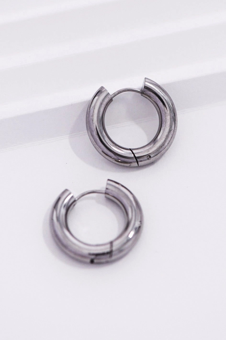 Bold silver-toned chunky hoops on a hand, showing their thick silhouette and 0.95 inch size.