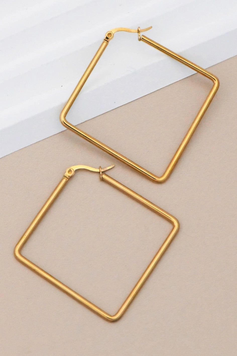 Modern 18K gold oversized square hoop earrings worn, highlighting their sharp and elegant geometric silhouette.