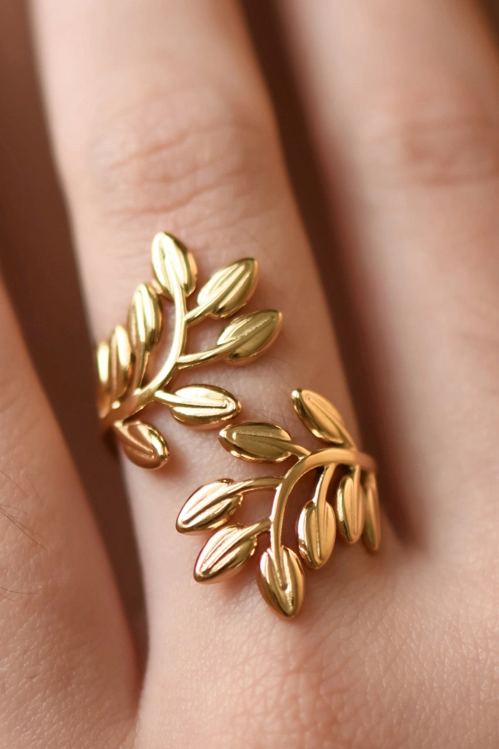 Feminine leaf-inspired gold ring worn on a finger, showcasing the adjustable botanical design.