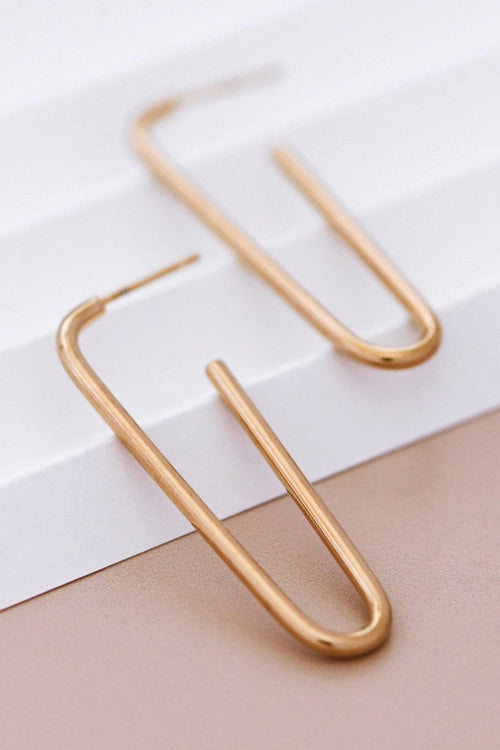 8K gold plated stainless steel classic tube hoop earrings held between fingers by Kogi Jewelry.
