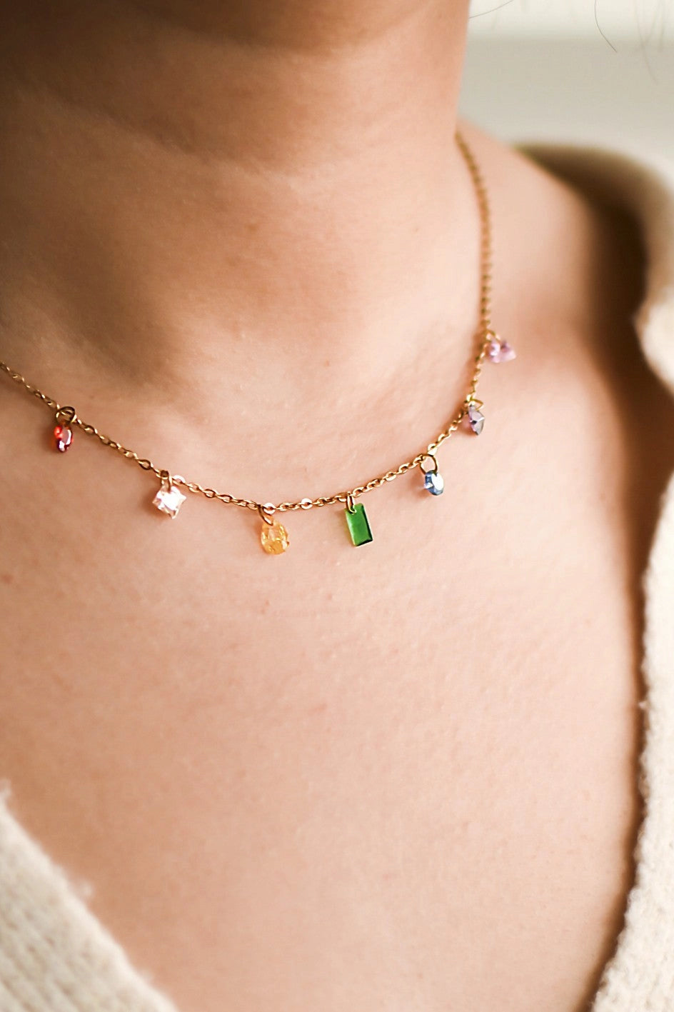 Full length view of the tarnish-free 18K gold plated colorful stone necklace, displaying the lobster clasp and extension chain on a hand.