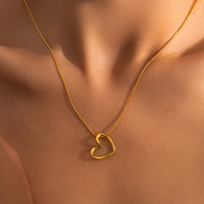 Minimalist gold chain necklace with a heart charm resting on a hand, showing its rich 18K gold finish.