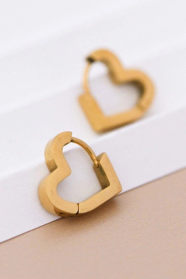 Dainty gold heart earrings resting on a hand, showing their petite 0.55 inch size and polished finish.