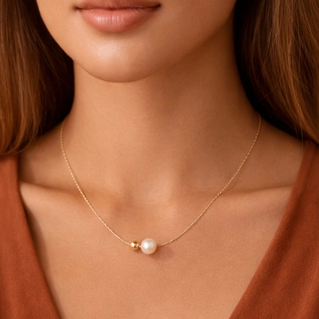 Elegant pearl and gold herringbone chain necklace resting on a hand, showing the front clasp detail.