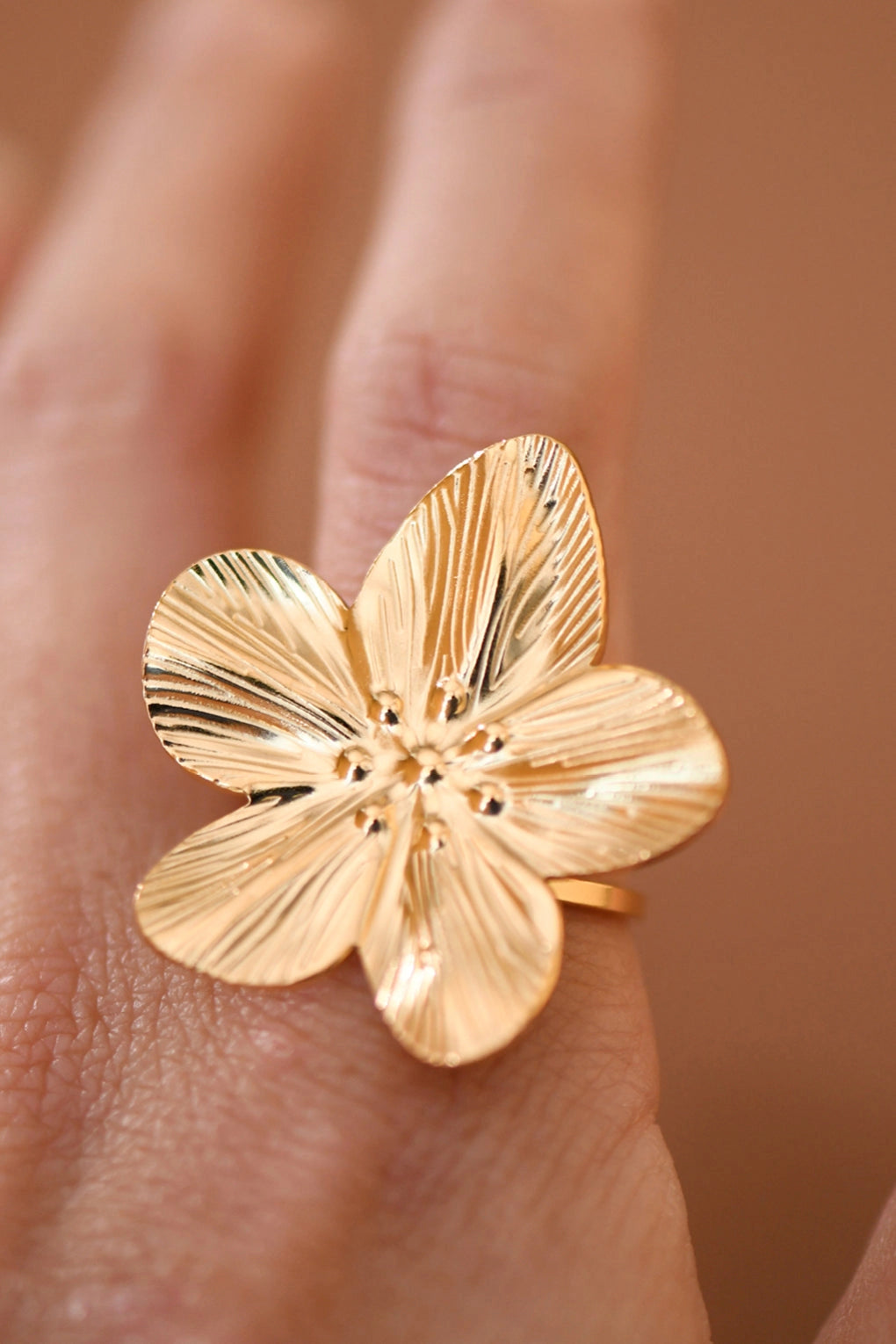 Close-up shot of an adjustable flower ring made of 18k gold plated stainless steel on a hand