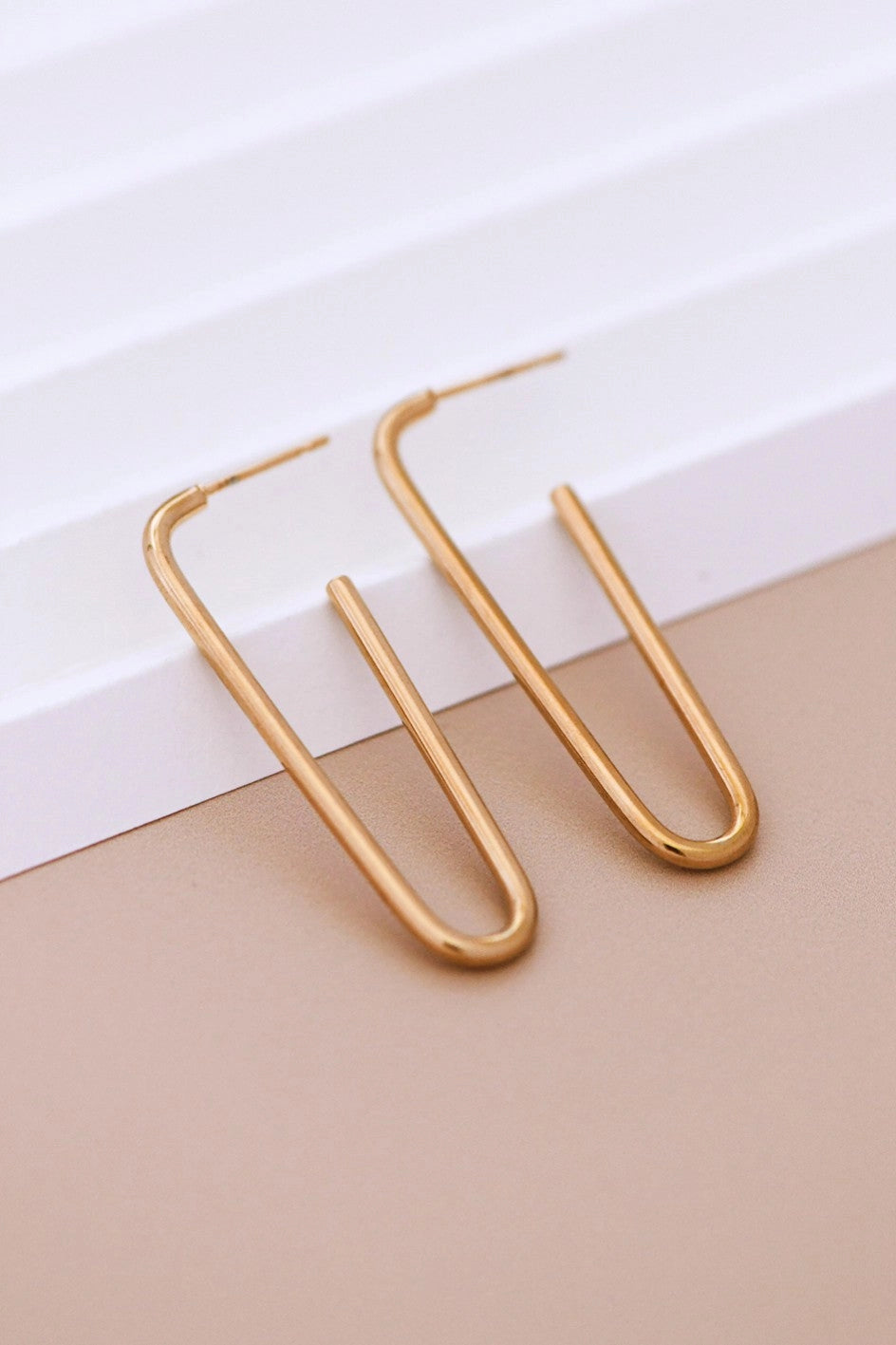Mid-sized gold polished hoop earring resting on a hand, showcasing its sleek 18K gold finish.