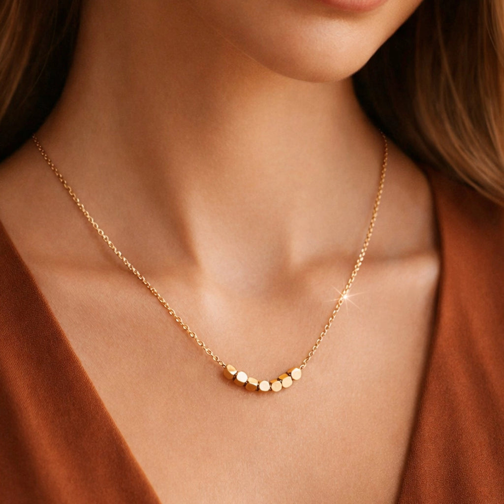 Dainty gold necklace with square beads worn on neck, showcasing its modern geometric style.