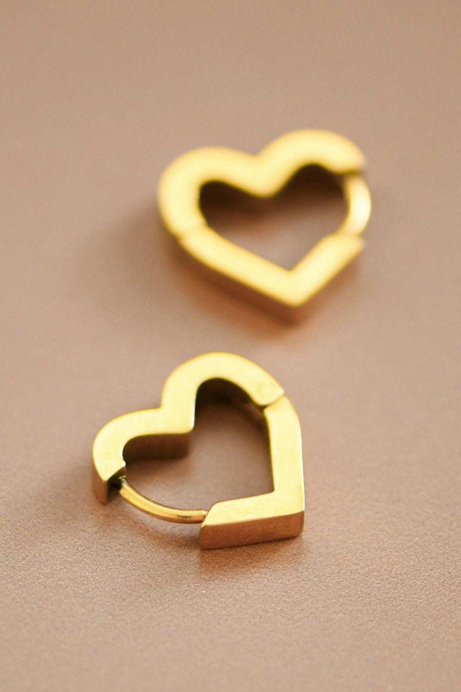 Close-up of the secure hinge closure and square-edge design of the gold heart huggies.