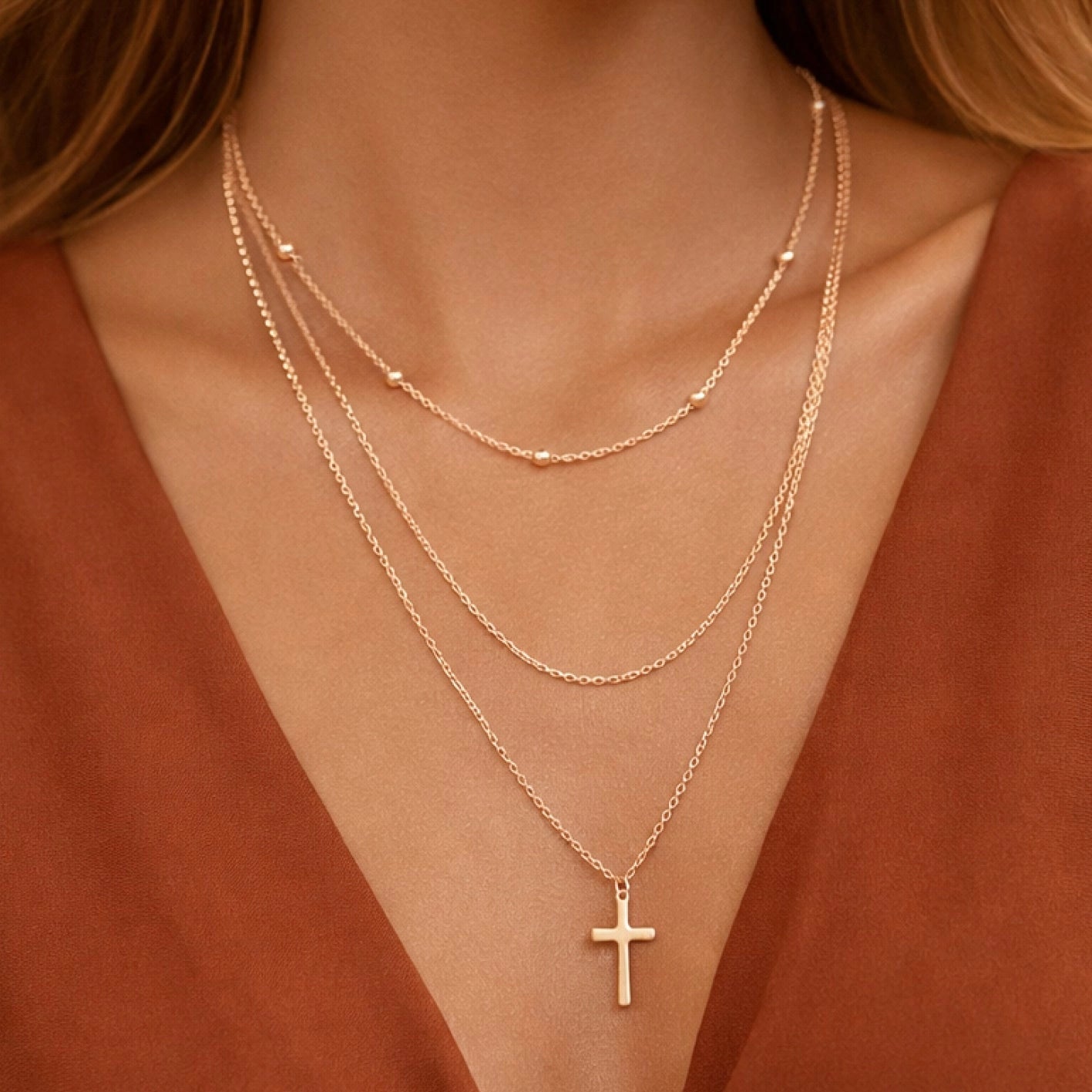 Woman wearing a multi-layer 18k gold plated cross necklace by Kogi Jewelry