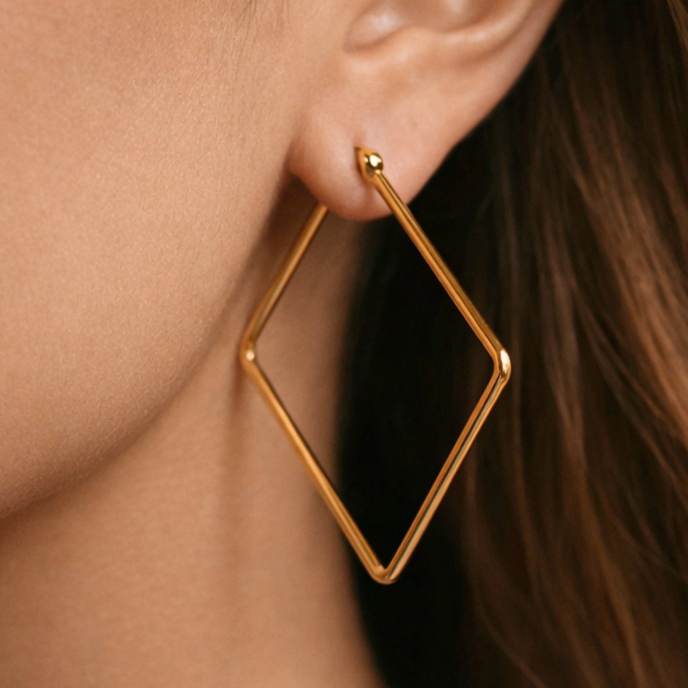 Oversized geometric gold square hoops resting on a hand, showing their impressive 2 inch scale.