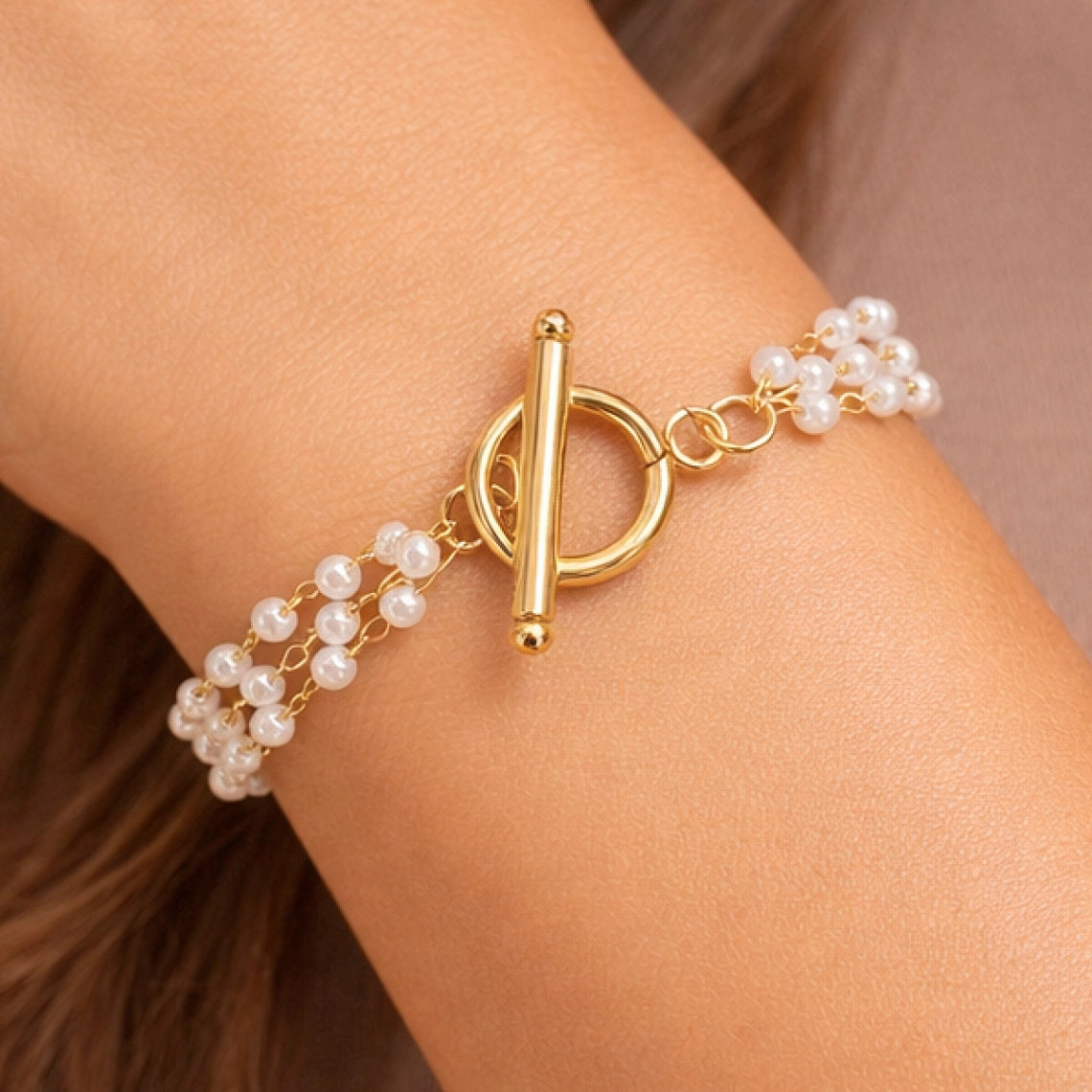 Woman wearing an 18k gold plated multi-layer pearl bracelet on her wrist
