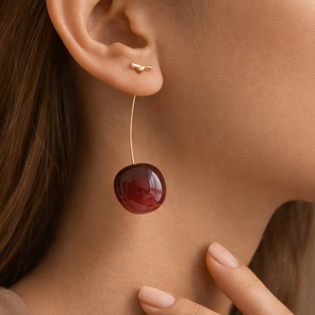 Woman wearing long 3D red cherry drop earrings showcasing the length and style