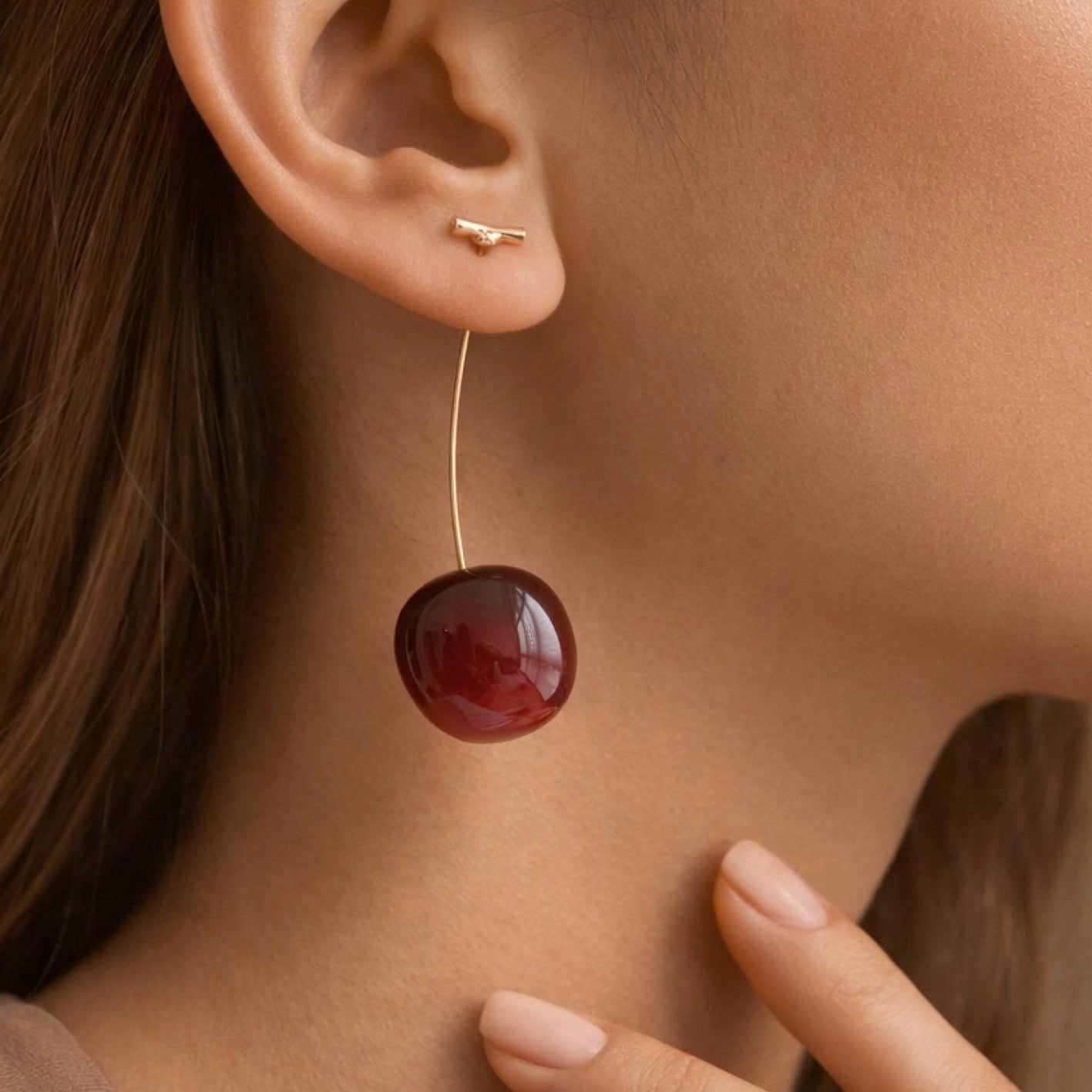 Woman wearing long 3D red cherry drop earrings showcasing the length and style