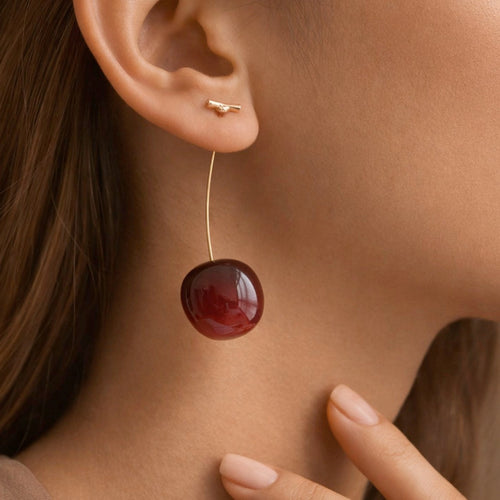 Woman wearing long 3D red cherry drop earrings showcasing the length and style
