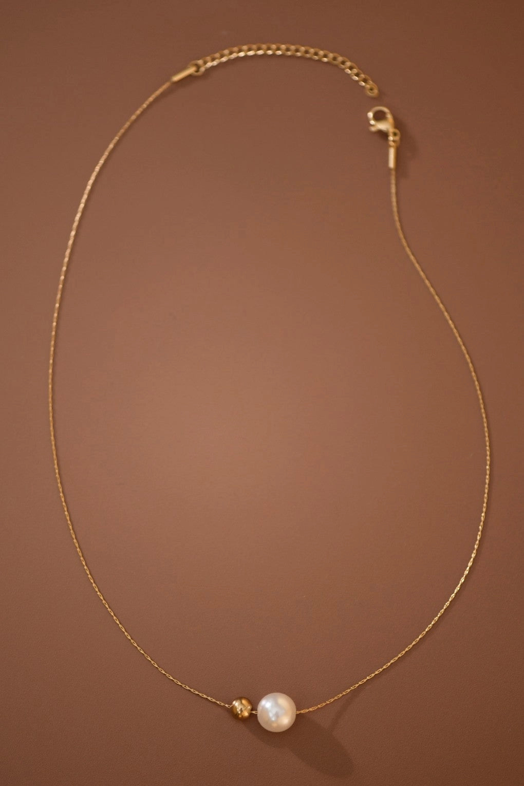 Close-up detail of the smooth herringbone chain and white pearls on the 18K gold plated Kogi Jewelry necklace.