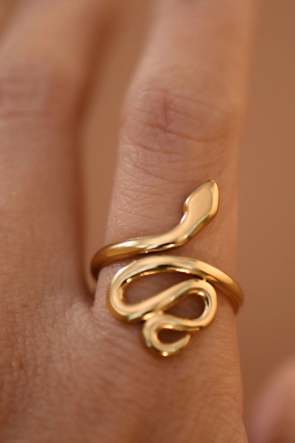 Minimalist modern snake-inspired gold ring with an adjustable open band design.