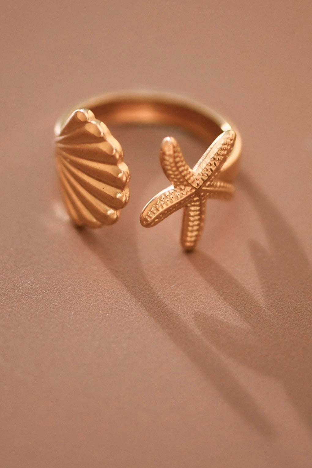 Detailed close-up of a tarnish-free gold starfish and shell ring for summer jewelry styling