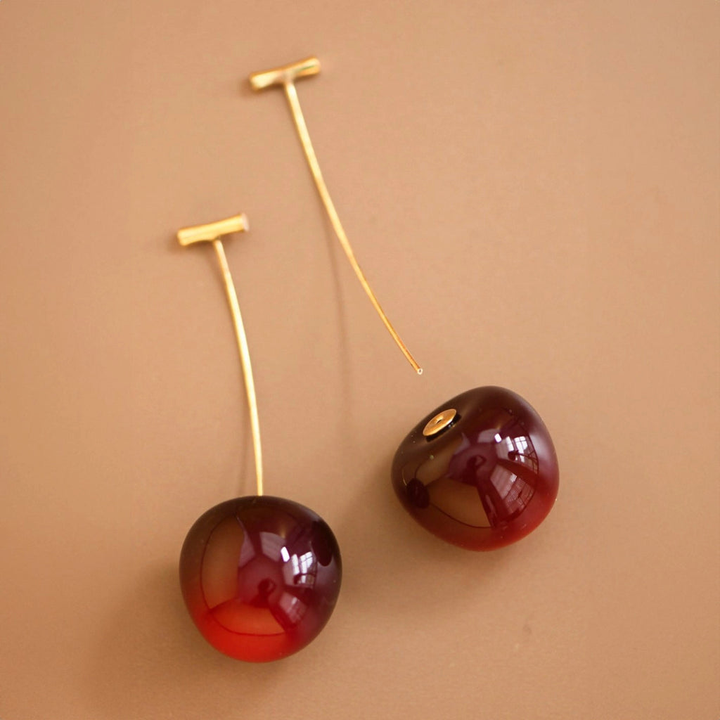 Close-up of a 3D cherry earring on ear highlighting the realistic red fruit design