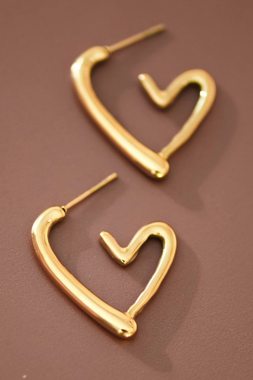 Modern chunky gold heart earrings worn, highlighting the romantic silhouette and minimalist style.