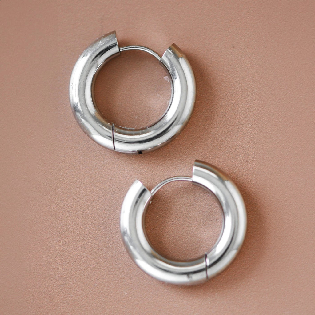 Modern polished stainless steel chunky hoops worn on the ear, showcasing a clean silver aesthetic