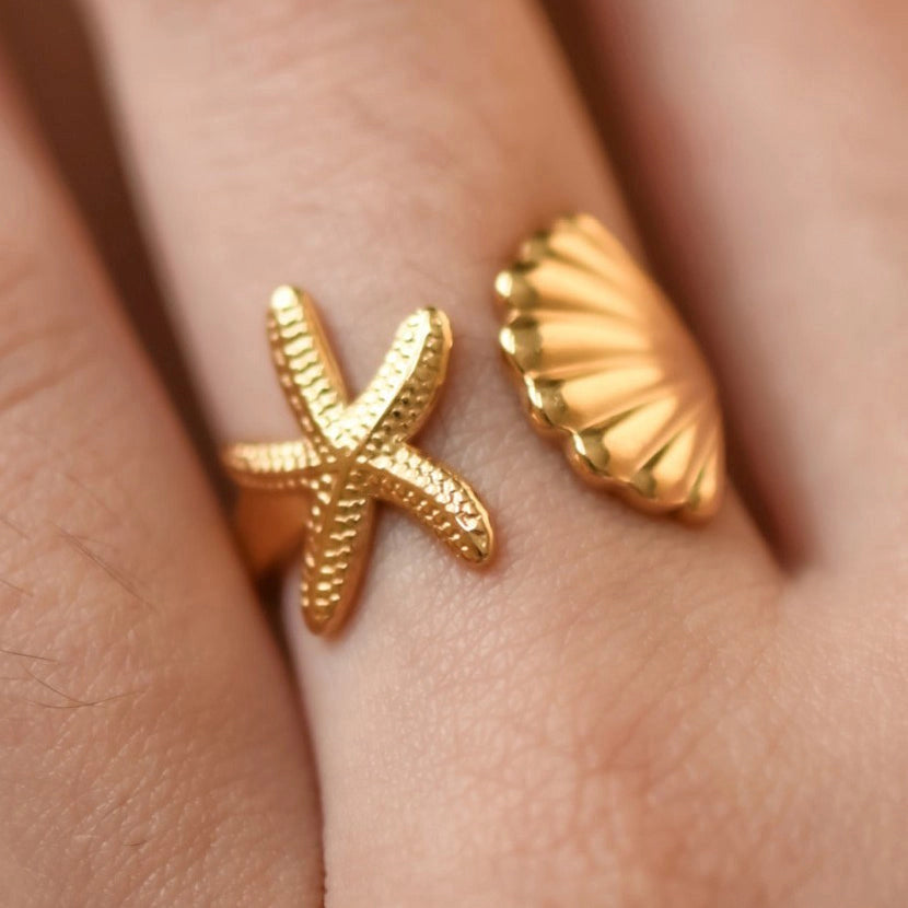 18K gold plated starfish and seashell adjustable ring on a woman's finger.