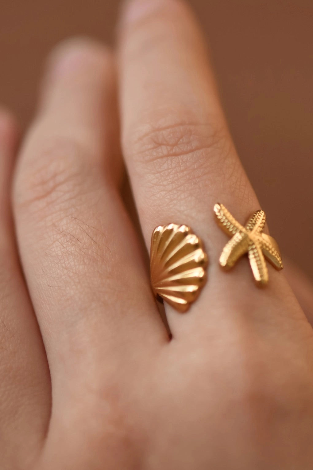 Detailed close-up of a tarnish-free gold starfish and shell ring showing premium 18K finish.