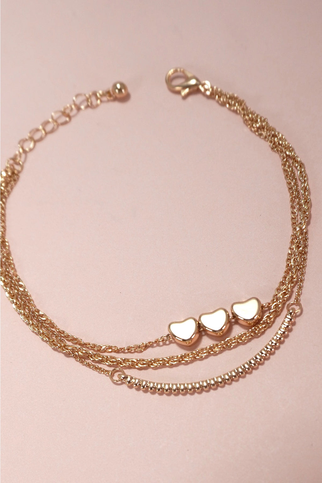 Polished gold multi-strand bracelet featuring paperclip and flat link chains with heart accents.