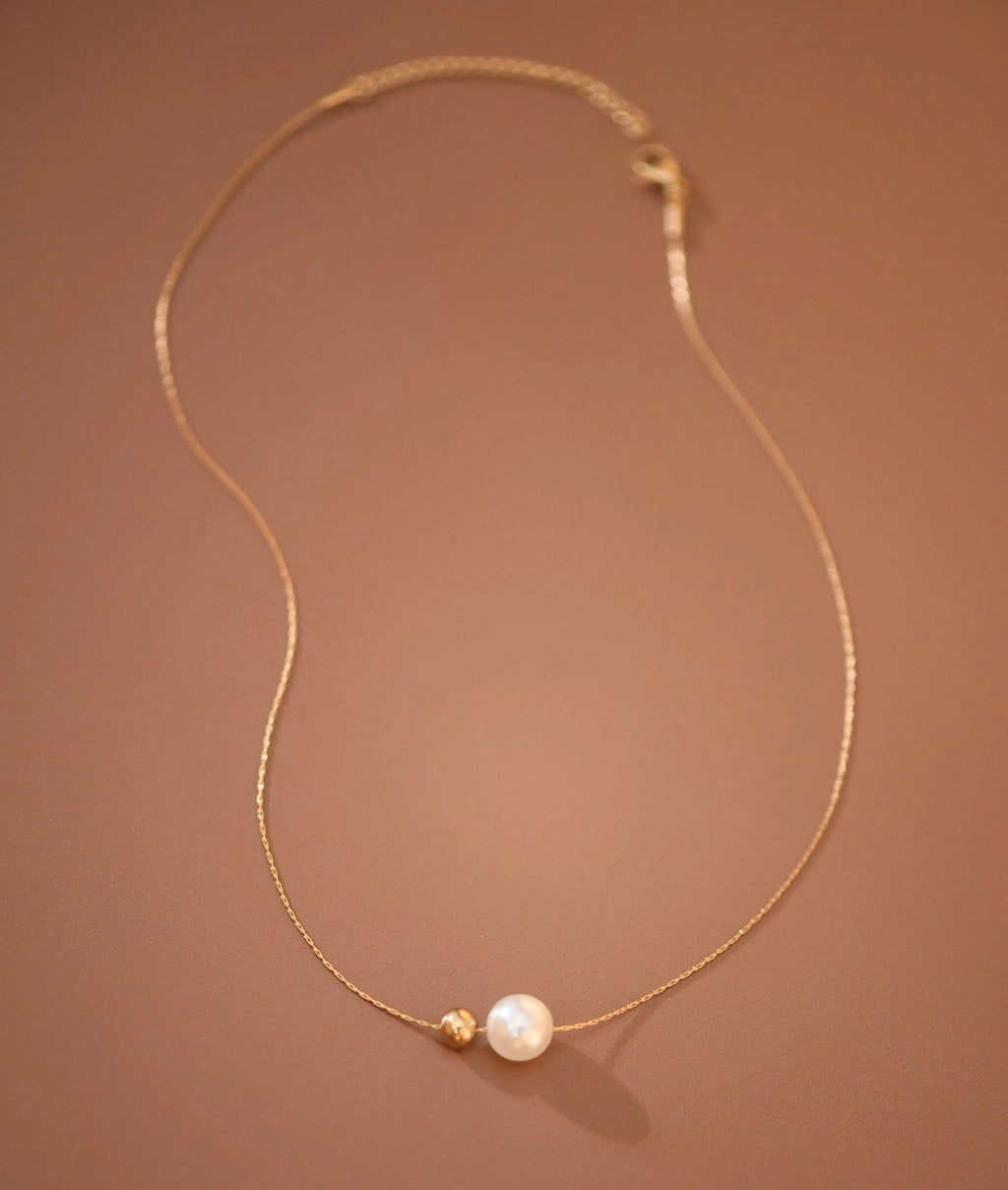 Full view of the tarnish-free 18K gold pearl and herringbone necklace with extension chain.