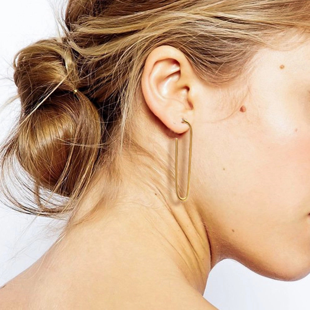 Pair of tarnish-free 18K gold plated tube hoop earrings on a hand, showing the rich golden color.